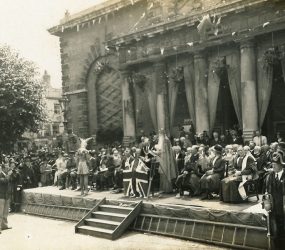 Audience and dignitaries seated on platform outside town hall
