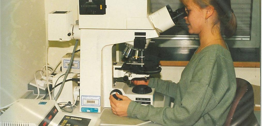 woman viewing samples through powerful multi-lens microscope