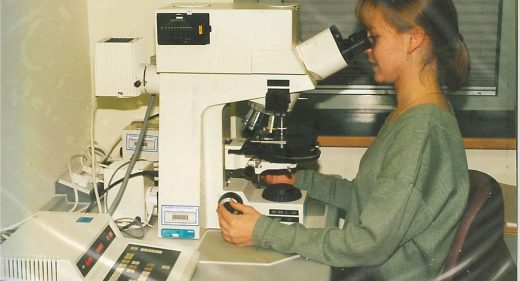 woman viewing samples through powerful multi-lens microscope