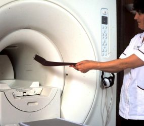 Nurse demonstrating magnet attracting the belt buckle which is pulled towards scanner
