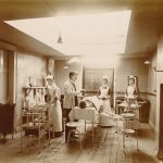 Patient on operating table with lighting, equipment nurses and doctor attending