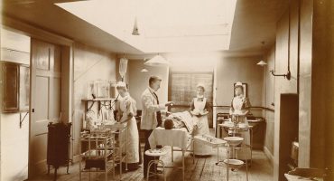 Patient on operating table with lighting, equipment nurses and doctor attending