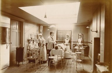 Patient on operating table with lighting, equipment nurses and doctor attending