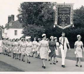Nurses in uniform with banner carried at front
