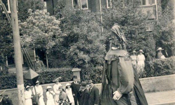 Giant wooden clothed figure walks alongside soldiers.