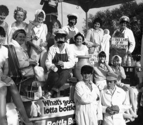 Staff dressed as milkmen carrying pints - banner on float reads 'what's gotta lotta bottle?'
