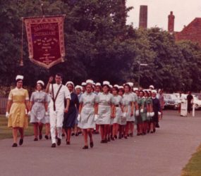 Nurses in uniform with standard carrier at front