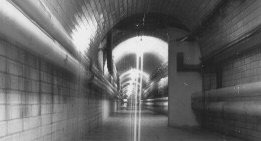 Black and white photo of tunnel with tiles and pipes