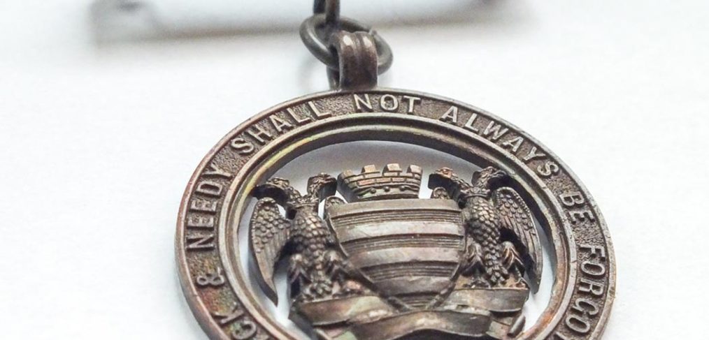 bronze metal badge with Salisbury city crest and Infirmary motto