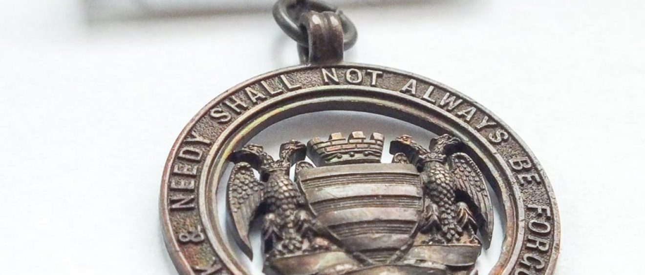 bronze metal badge with Salisbury city crest and Infirmary motto
