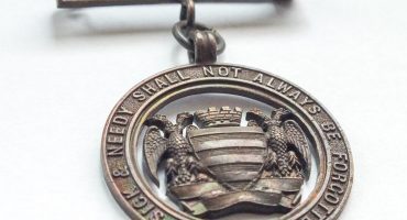 bronze metal badge with Salisbury city crest and Infirmary motto