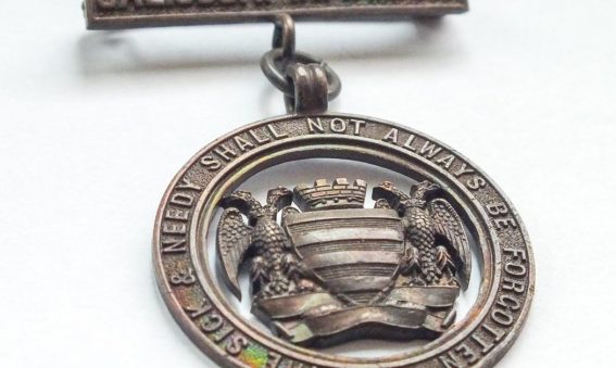 bronze metal badge with Salisbury city crest and Infirmary motto