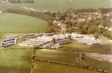 A colour aerial view of hospital huts and green fields beyond