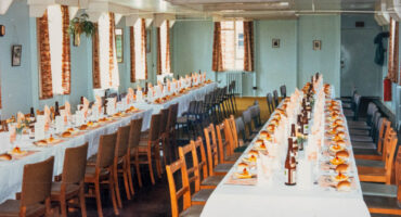 A colour photograph of 2 long tables laid up for lunch with bottles