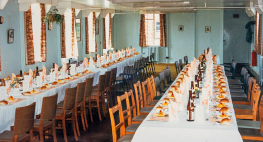 A colour photograph of 2 long tables laid up for lunch with bottles