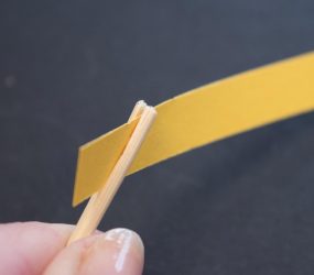 strip of paper held in slit of one end of wooden skewer