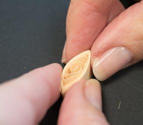 using fingers to pinch both edges of paper coil to form a diamond shape