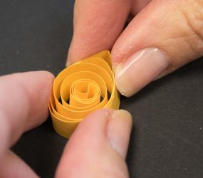 using fingers to pinch one edge of paper coil to form a point