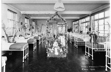 Children in beds and cots with ward centrepiece of flowers and dolls