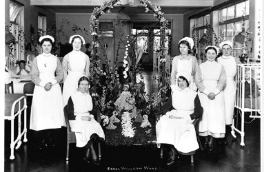 Nurses gathered round ward centrepiece of dolls and flowers