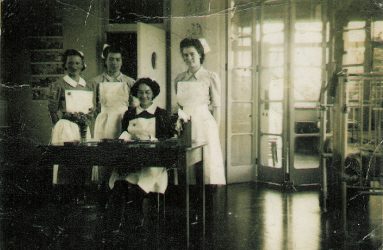 Nurses standing behind desk on ward