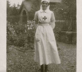 Nurse stands in the garden, church in the background