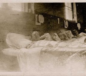 Three soldiers in bed pose for the camera