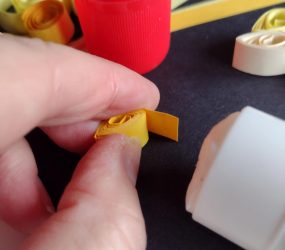 gluing the end of the tightly wound strip of paper