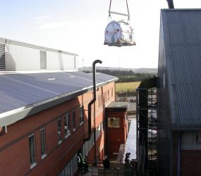 MRI scanner on the end of crane hook about to be lowered down towards the building