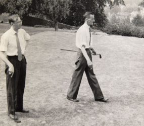 Two men with golf clubs on the grass