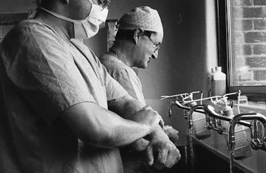 staff in scrubs and mask washing their hands