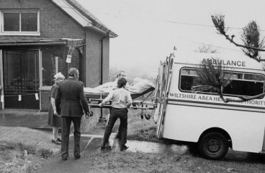 Patient on bed being loaded into back of ambulance