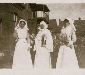 Nurses and nun in uniforms posing in garden outside hospital