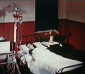 Female patient in bed with dialysis machine attached to arm