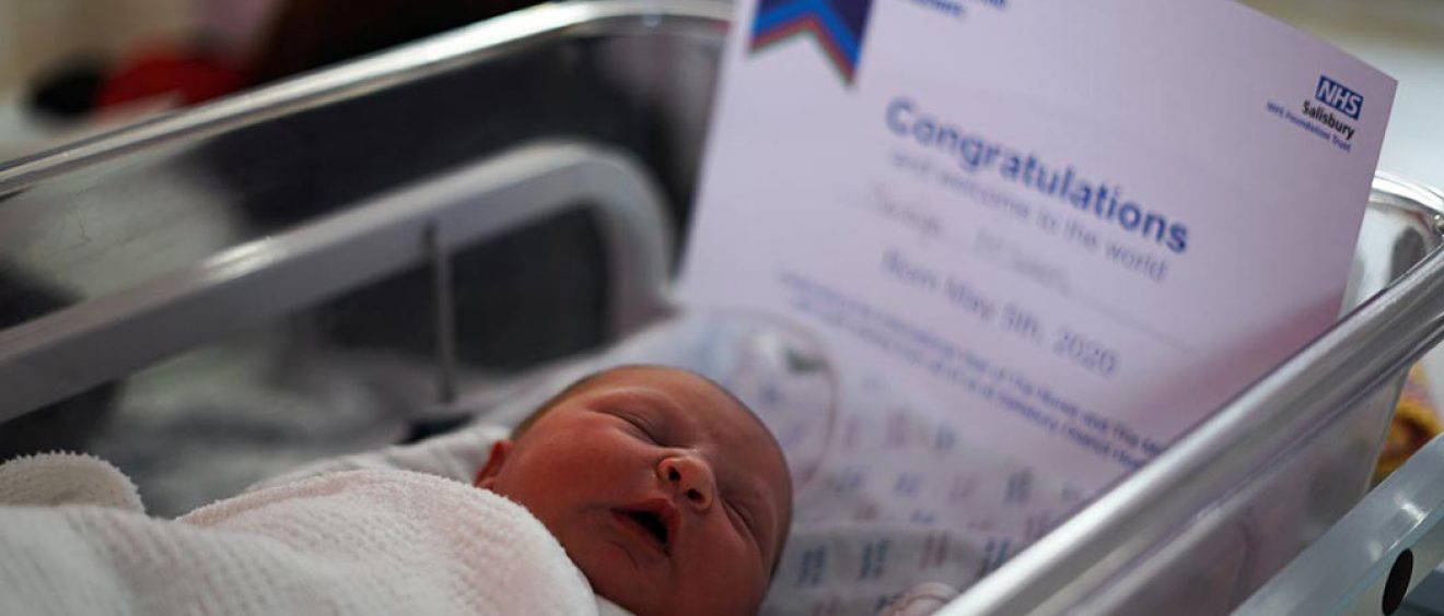 newborn baby in cot with certificate