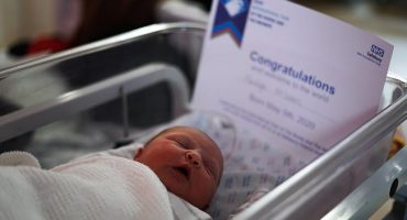newborn baby in cot with certificate