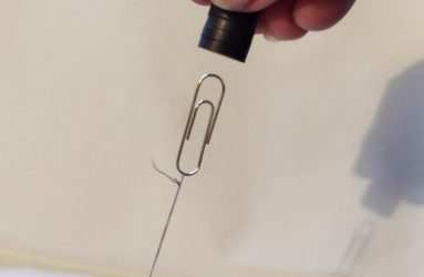 paper clip tied down with cotton thread attracted to the magnets held just above