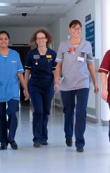 nurses in scrubs walking along corridor