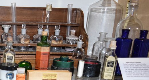clear glass bottles and green and blue hexagonal glass bottles with stoppers