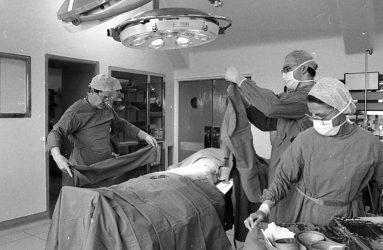 patient on table, doctors and nurses in scrubs preparing to operate