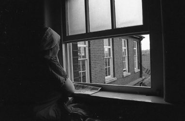 staff member in scrubs looking out of window