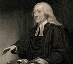 Engraved black and white print of John Wesley preaching
